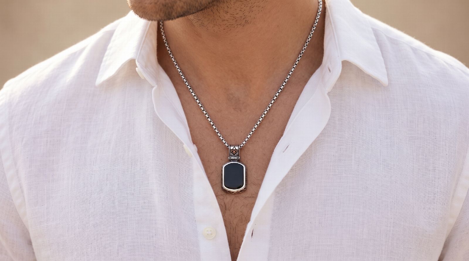 Man wearing a sterling silver round box chain with a black onyx pendant