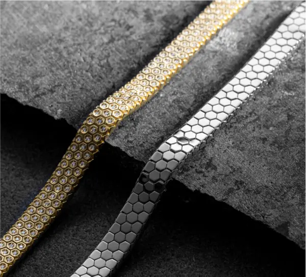Gold and silver hexagon link bracelets on dark stone